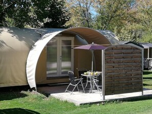 Een klein, gedeeltelijk open constructie met een glazen deur, een patio tafel en een stoel.