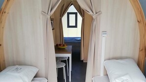 Une pièce confortable avec deux lits, une petite table sur laquelle se trouve un saladier rempli de fruits, et une fenêtre.
