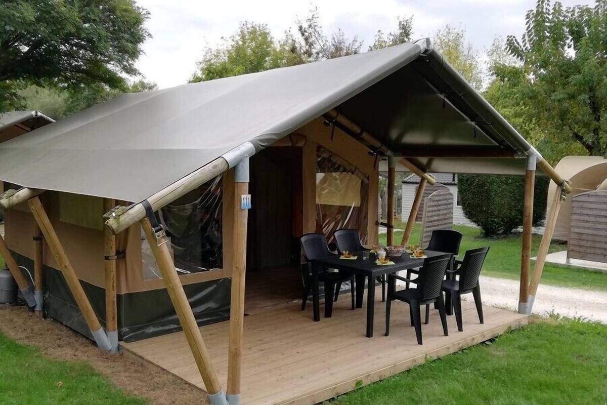 Une tente dotée d’une terrasse en bois et d’une table avec des chaises.