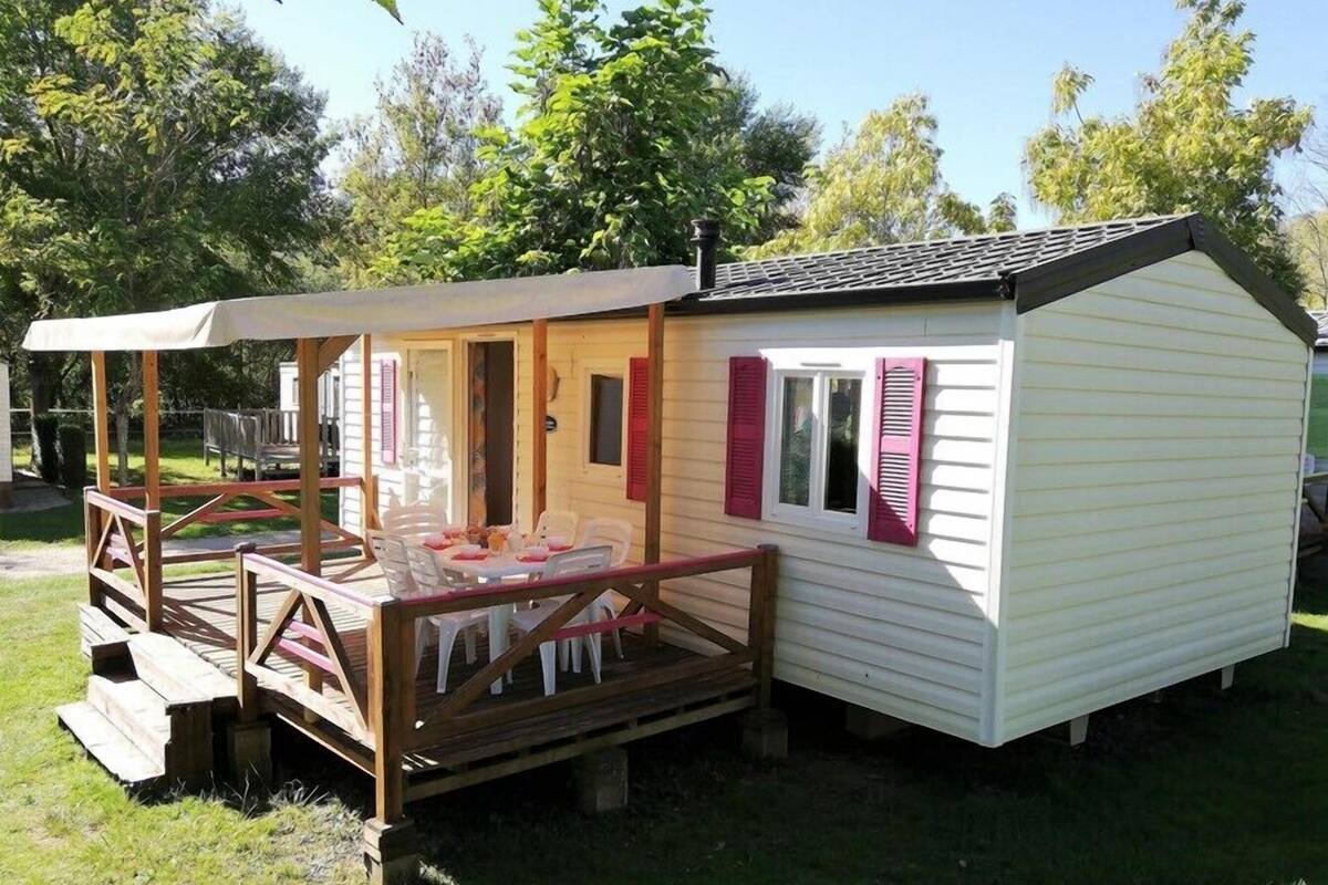 Une petite cabane en bois avec une véranda, une table à manger et des chaises.