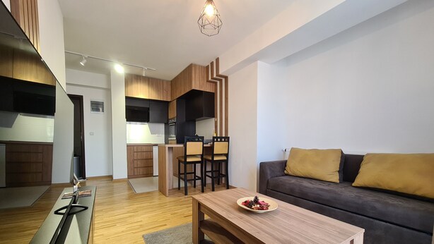 Uma sala de estar moderna com uma mesa de centro de madeira, um sofá com almofadas e um espaço de refeições com cadeiras.