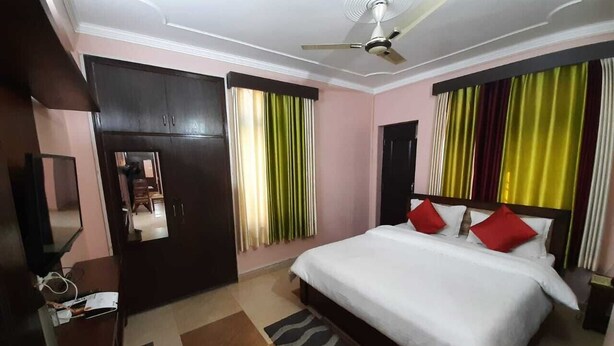 A hotel room with a bed, a wardrobe, a desk, and a ceiling fan. - Hill View Homes (Nainital)