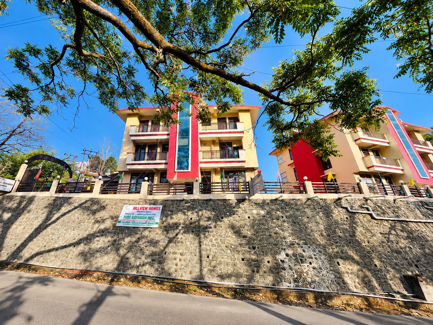 Un edifici d'àmbitós, amb balcons, un mur de pedra de sostreganç i un cartell de Hillview Homes.
