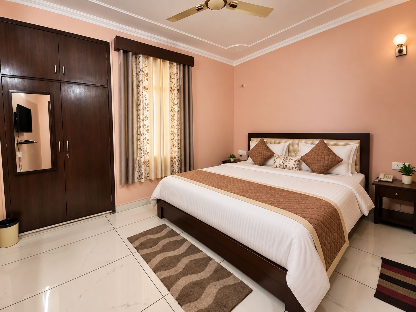 Quarto com cama, guarda-roupa, ventoinha no teto, mesa de cabeceira e luminária na parede.