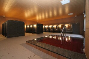 A swimming pool with a red water feature, surrounded by benches and a tiled floor. - Fujizakura Hotel (Oyama)