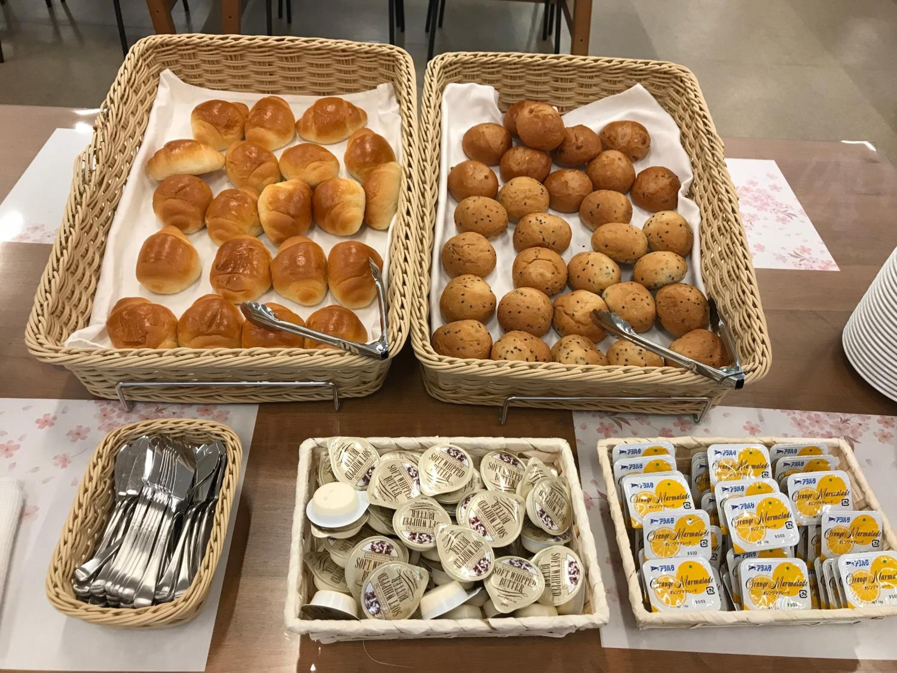Two wicker baskets filled with bread rolls and butter tubs.