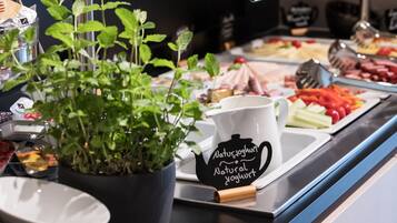 A buffet setup with various food items, a plant, and a jug labeled "Natur Yoghurth."