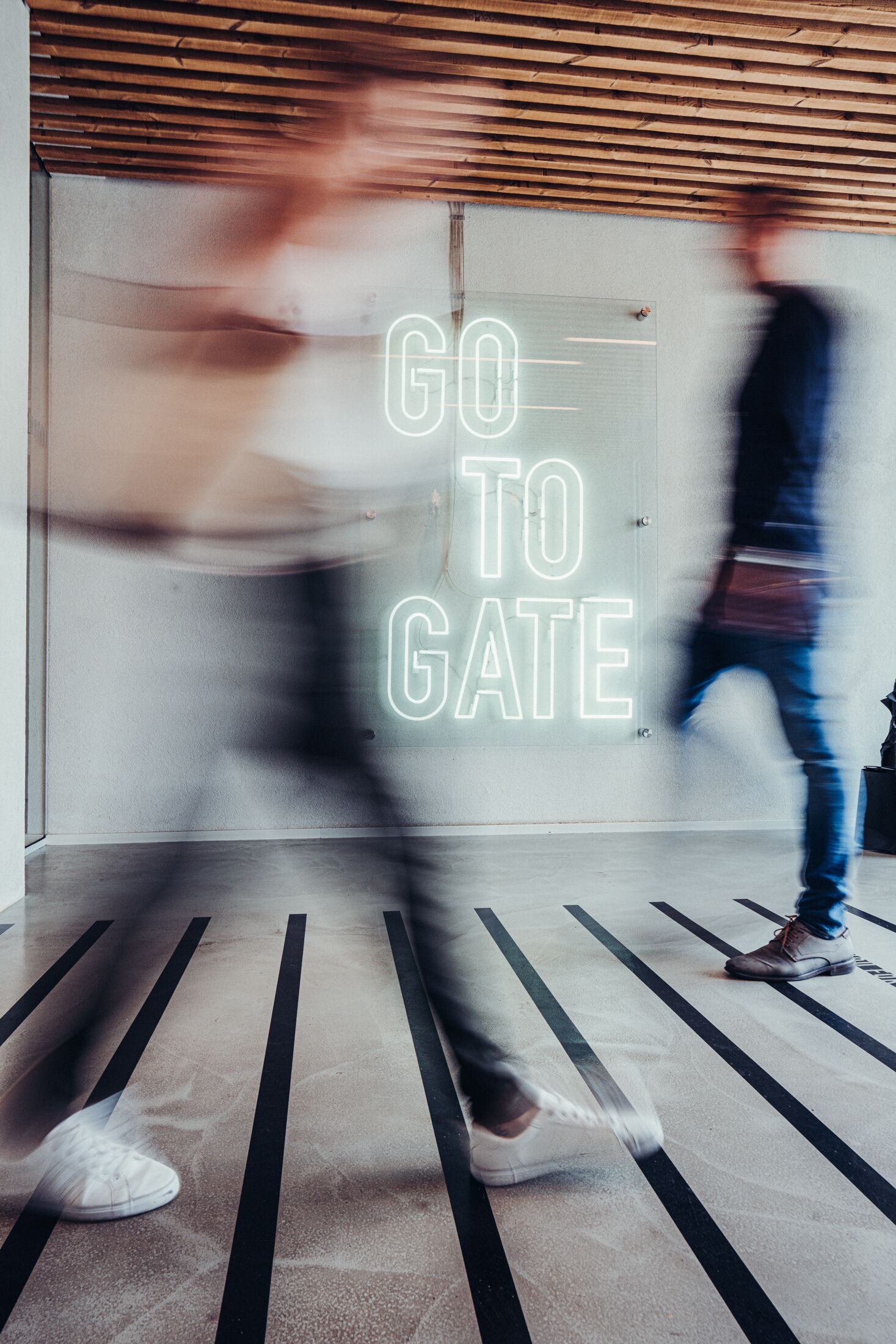 A person walking past a neon sign that reads "GO TO GATE".