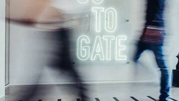 A person walking past a neon sign that reads "GO TO GATE".