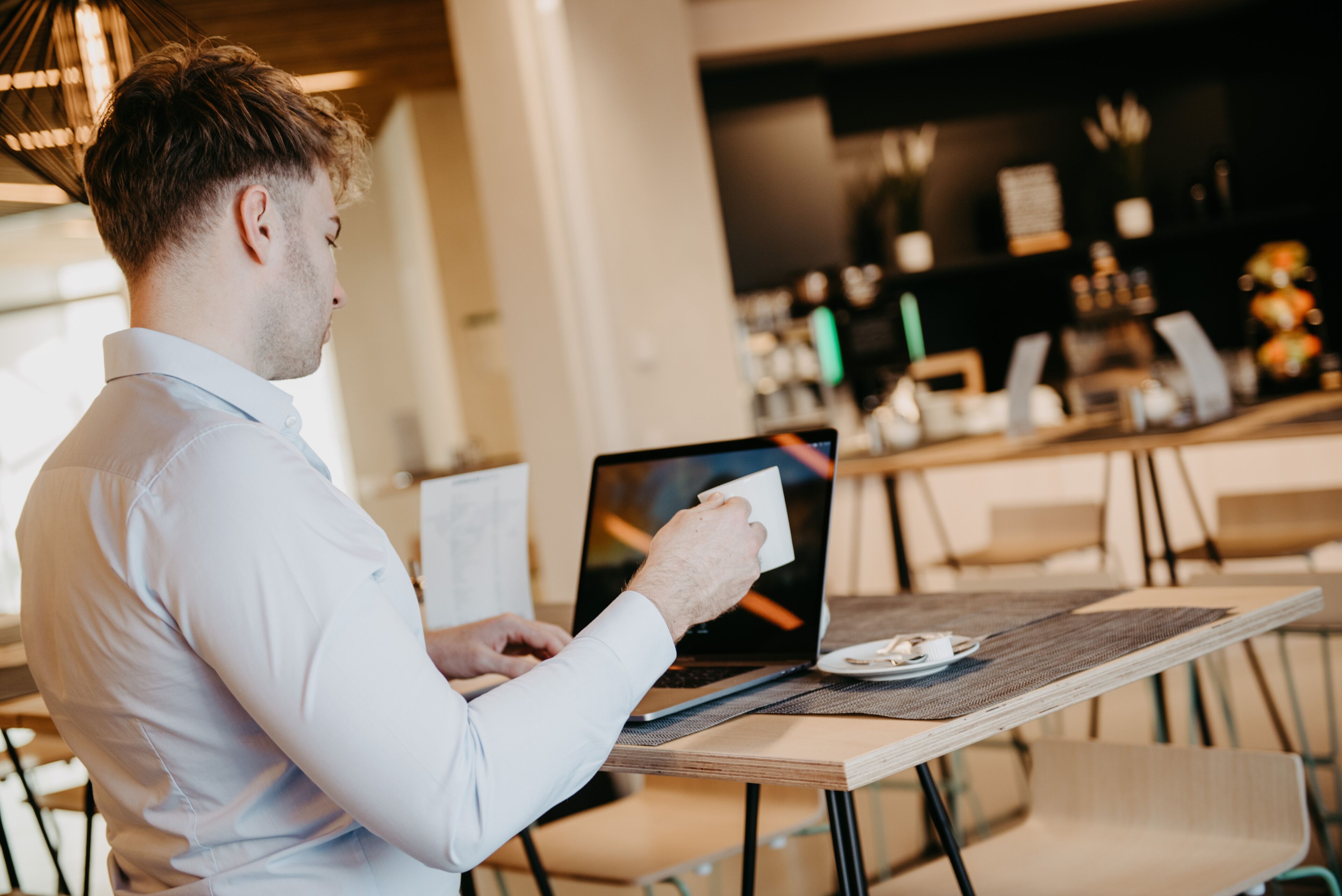 Une personne utilisant un ordinateur portable à une table dans un café.