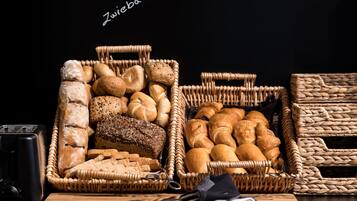 Une variété de pains et de viennoiseries présentés dans des paniers en osier, un grille-pain et une paire de ciseaux posés sur une table en bois.
