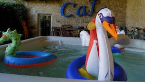 An indoor swimming pool with inflatable swans and a green inflatable shark.