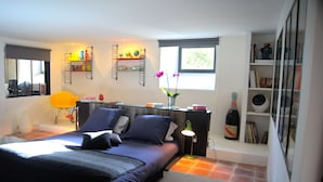 A modern bedroom with a bed, bedside tables, a lamp, a window, and a bookshelf.