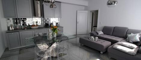 Una cocina moderna con armarios grises, una mesa de comedor de vidrio y un sofá gris.