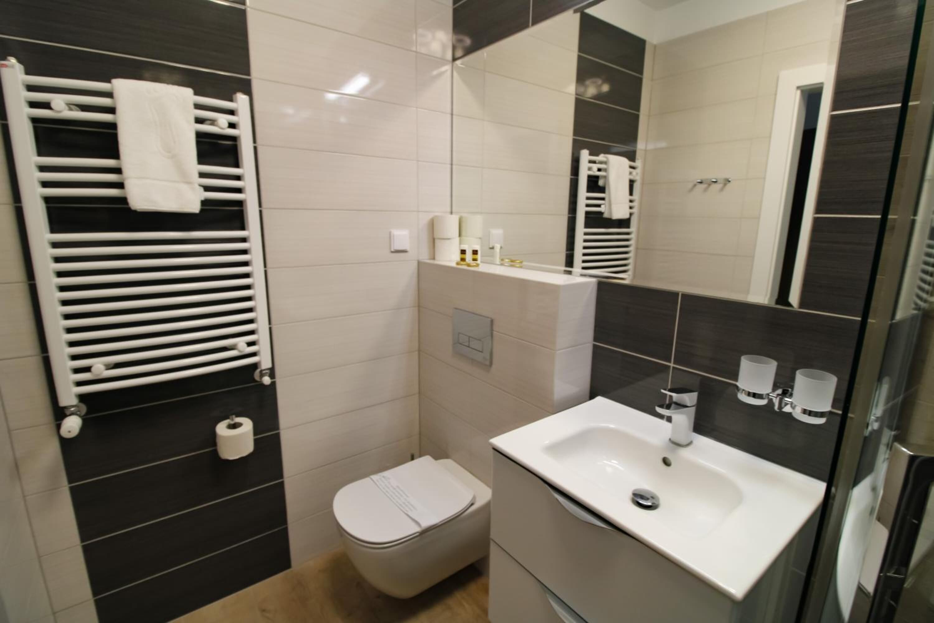 Un bagno moderno con un lavandino bianco, un water e un porta asciugamani.
