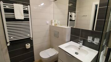 Un bagno moderno con un lavandino bianco, un water e un porta asciugamani.