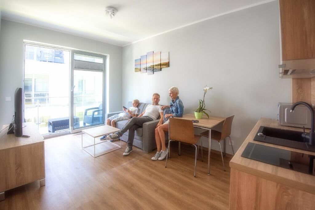 A modern living room with a sofa, a dining table, and a kitchen area with a sink and a microwave.
