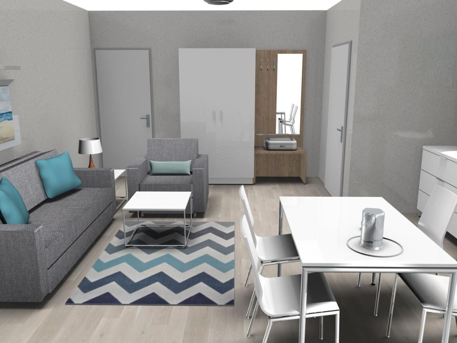 A modern, compact living space with a grey sofa, a small table, a dining table with chairs, and a kitchen area with a white cabinet and a sink.