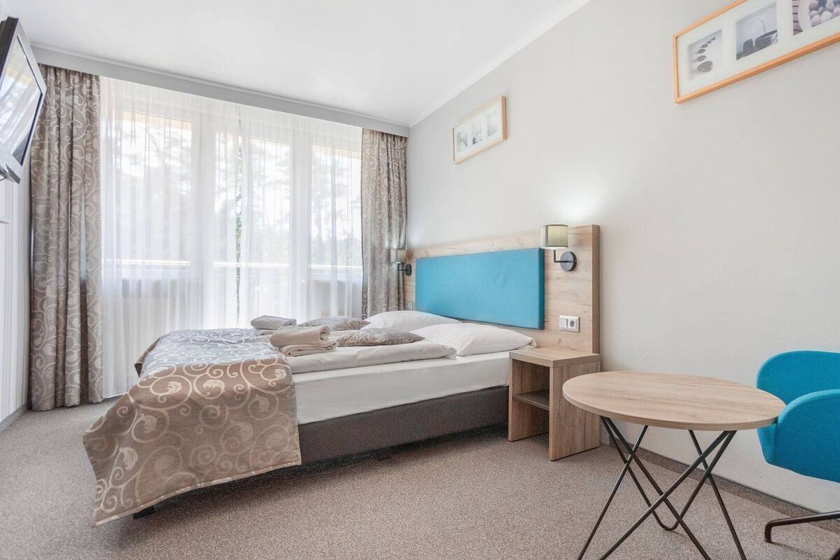 Ein Hotelzimmer mit einem Bett, einem Nachttisch, einem Sessel und einem kleinen runden Tisch.