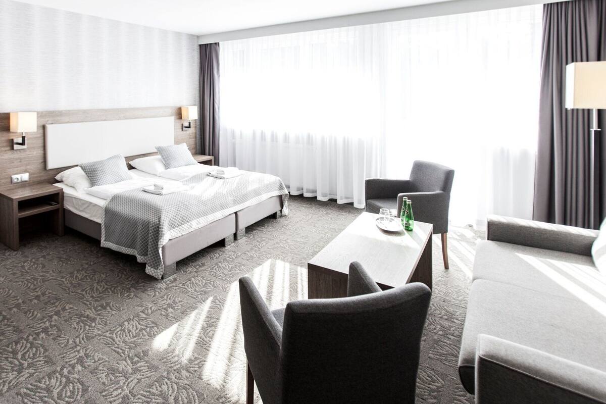 Ein Hotelzimmer mit Bett, Schreibtisch, Stuhl und einer Sitzecke.