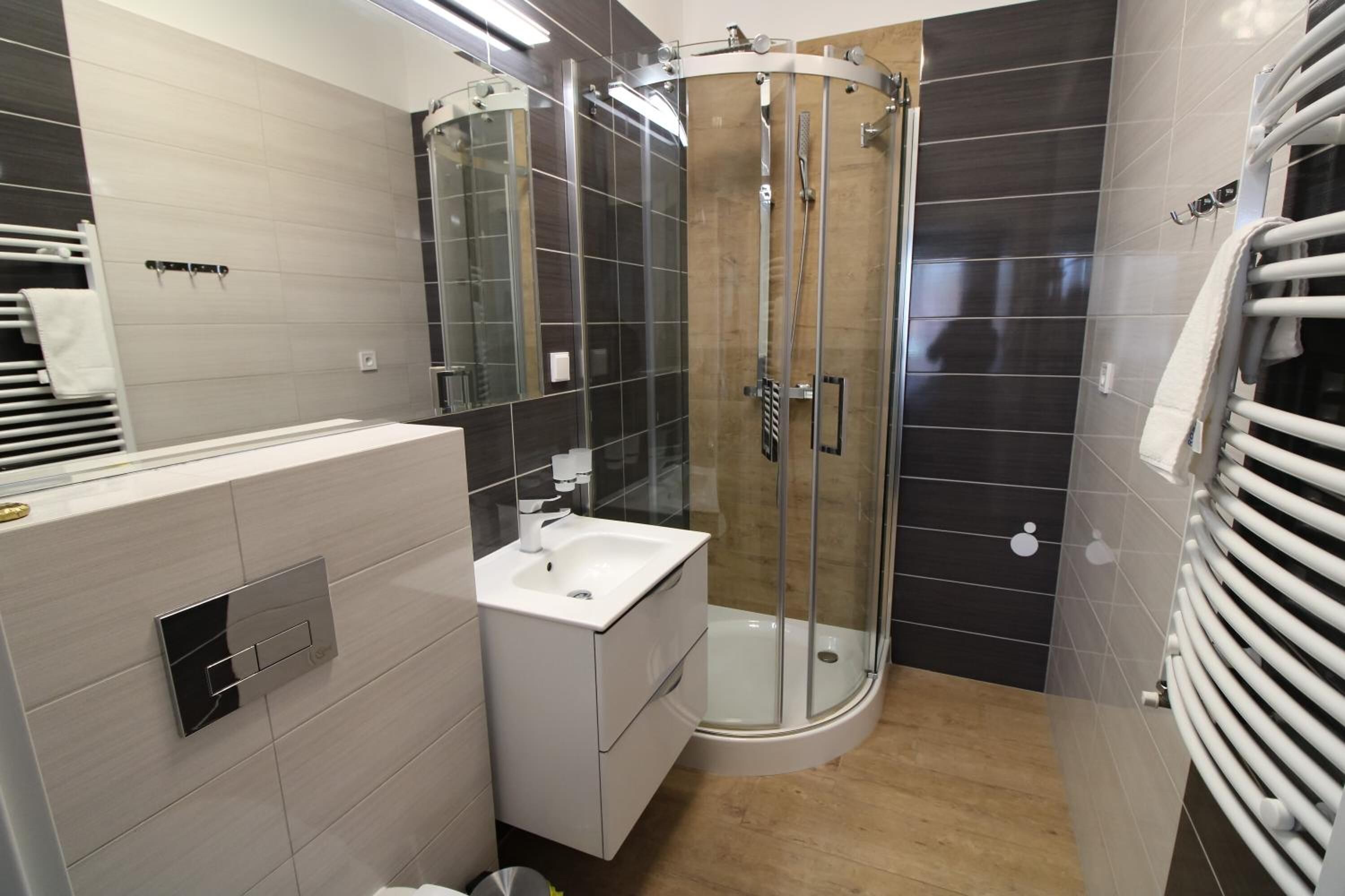 A modern bathroom with a glass-enclosed shower, a white sink, and a towel rack.
