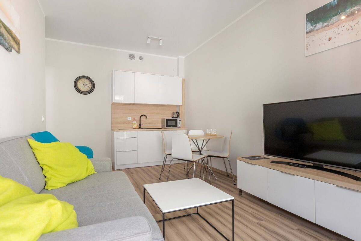Ein kompakter Wohnbereich mit Sofa, Couchtisch, Fernseher, einer Küchenzeile und einem Essbereich.