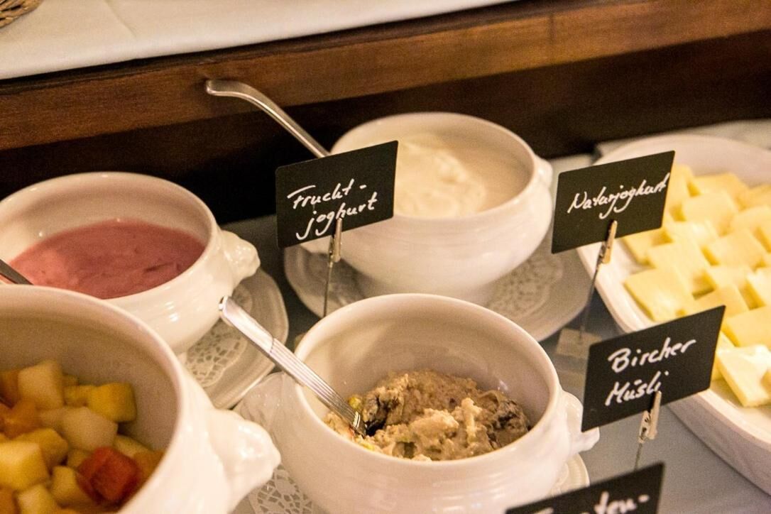 Variedad de alimentos que incluyen yogur, queso y un plato con trozos de fruta y carne.