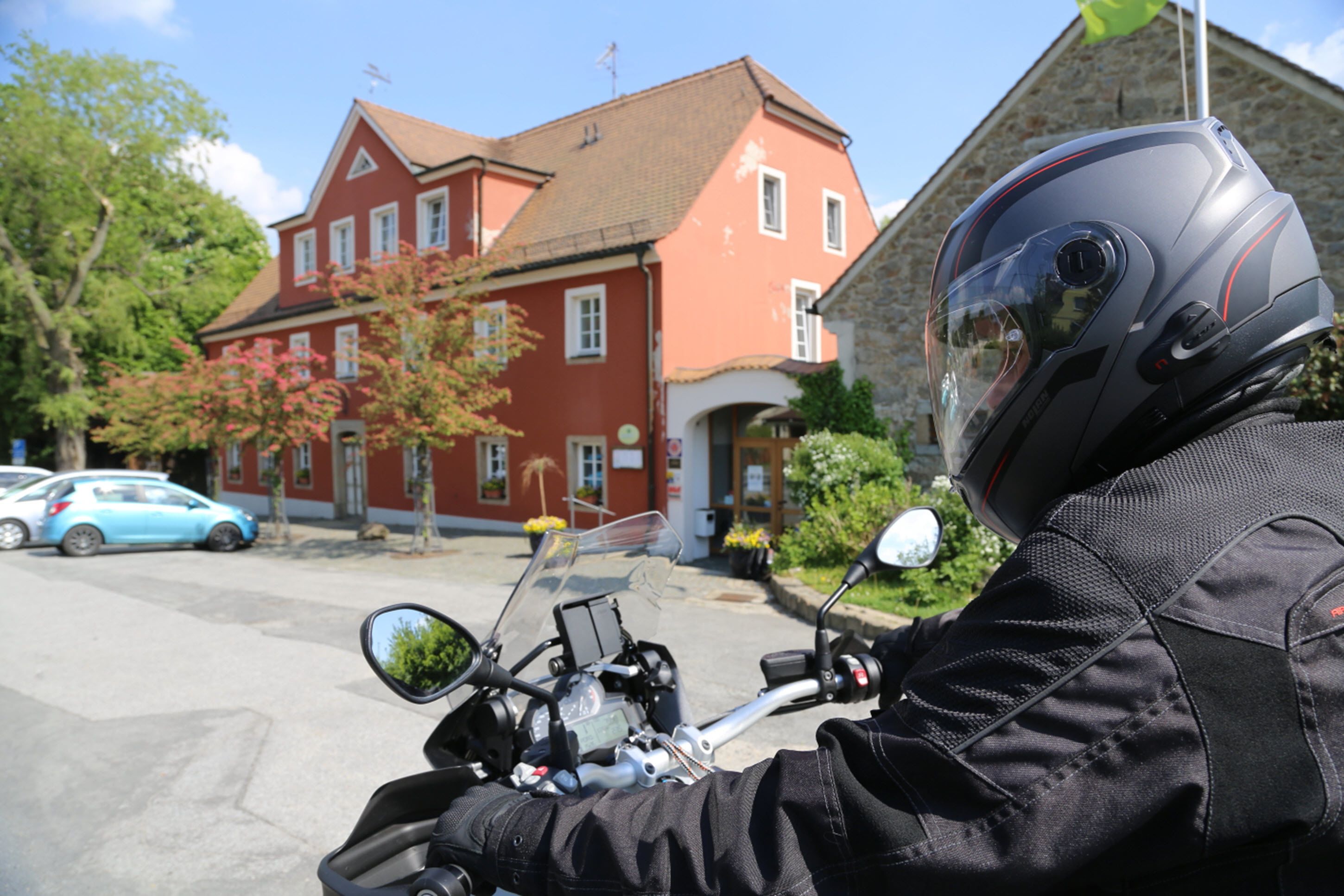 A motorcycle parked in front of a red building with a stone facade.