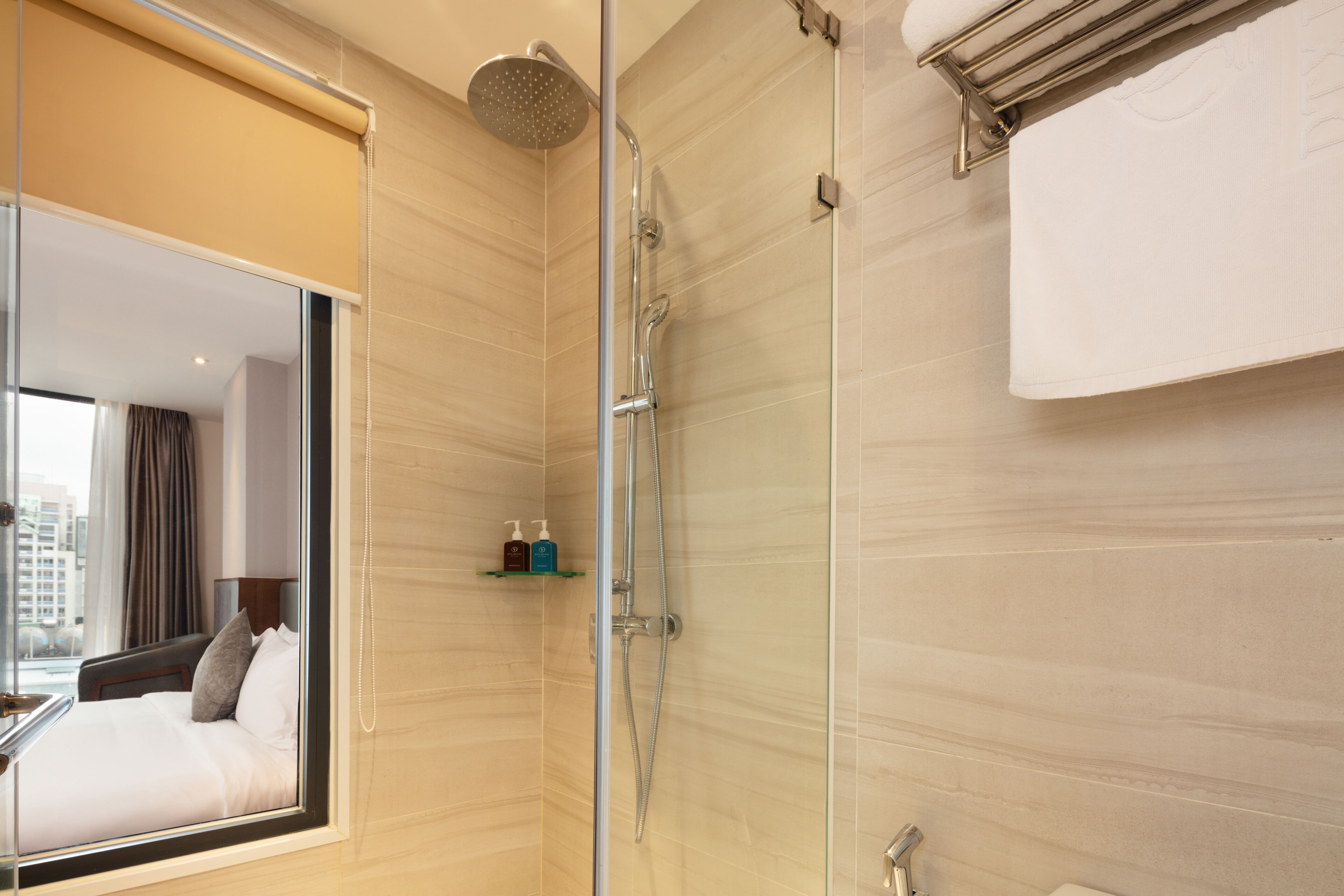 A modern bathroom with a glass shower enclosure, a large mirror, and a towel rack.
