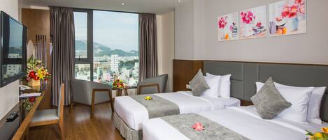 A hotel room with two beds, a desk, a TV, and a city view.