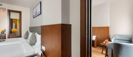 A hotel room with a bed, bedside table, and a desk with a chair.