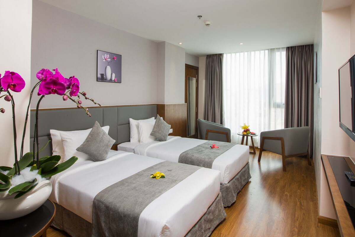 Ein Hotelzimmer mit zwei Betten, einem Fernseher, einem Schreibtisch und einem Stuhl.