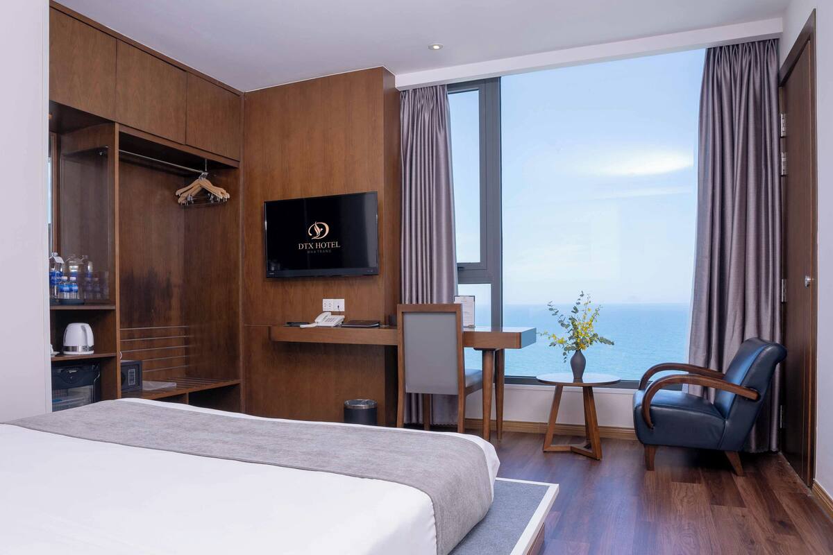 Ein Hotelzimmer mit Bett, Schreibtisch, Stuhl, Fernseher und Meerblick.