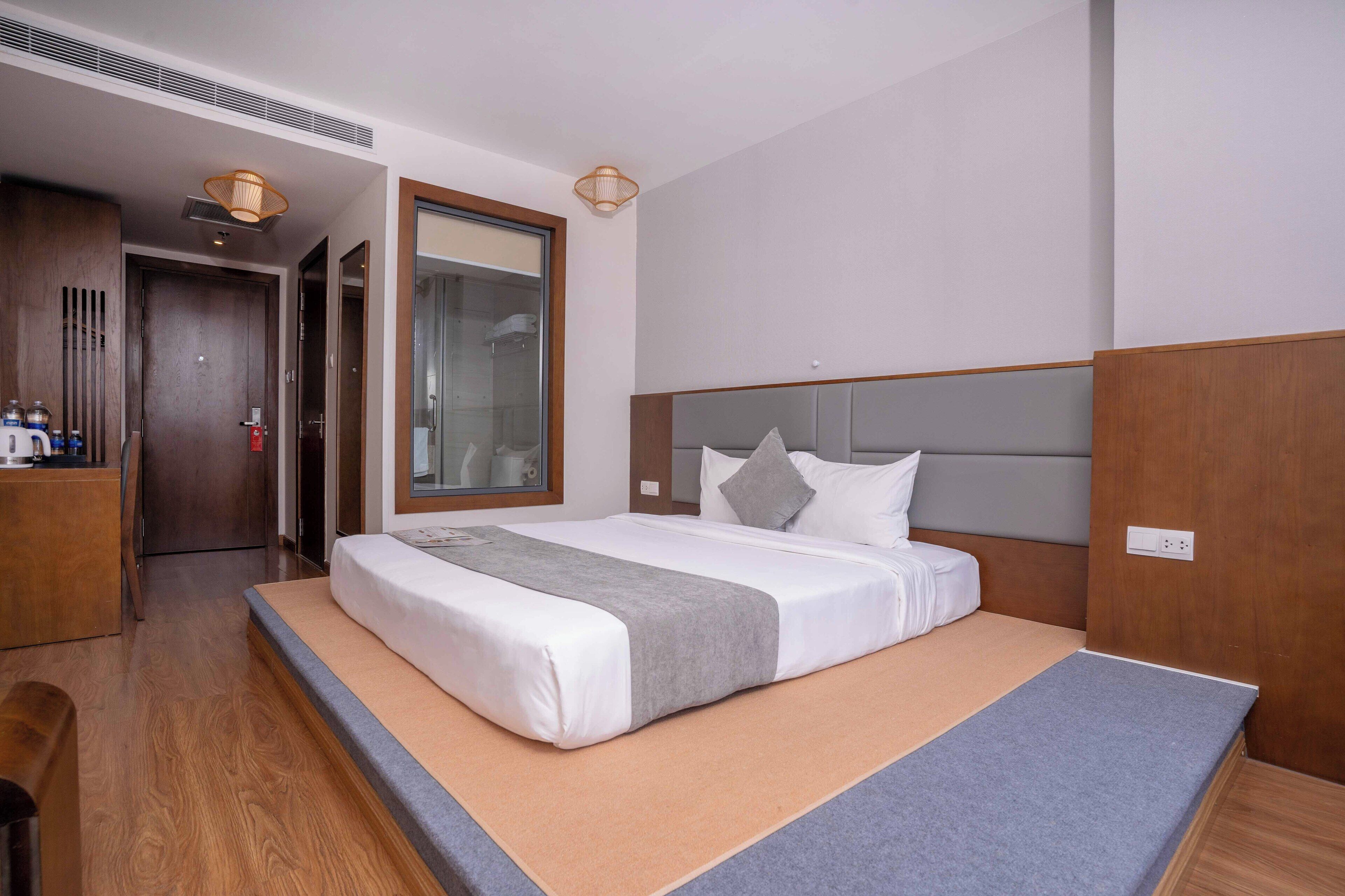 A hotel room with a bed, a desk, and a mirror.