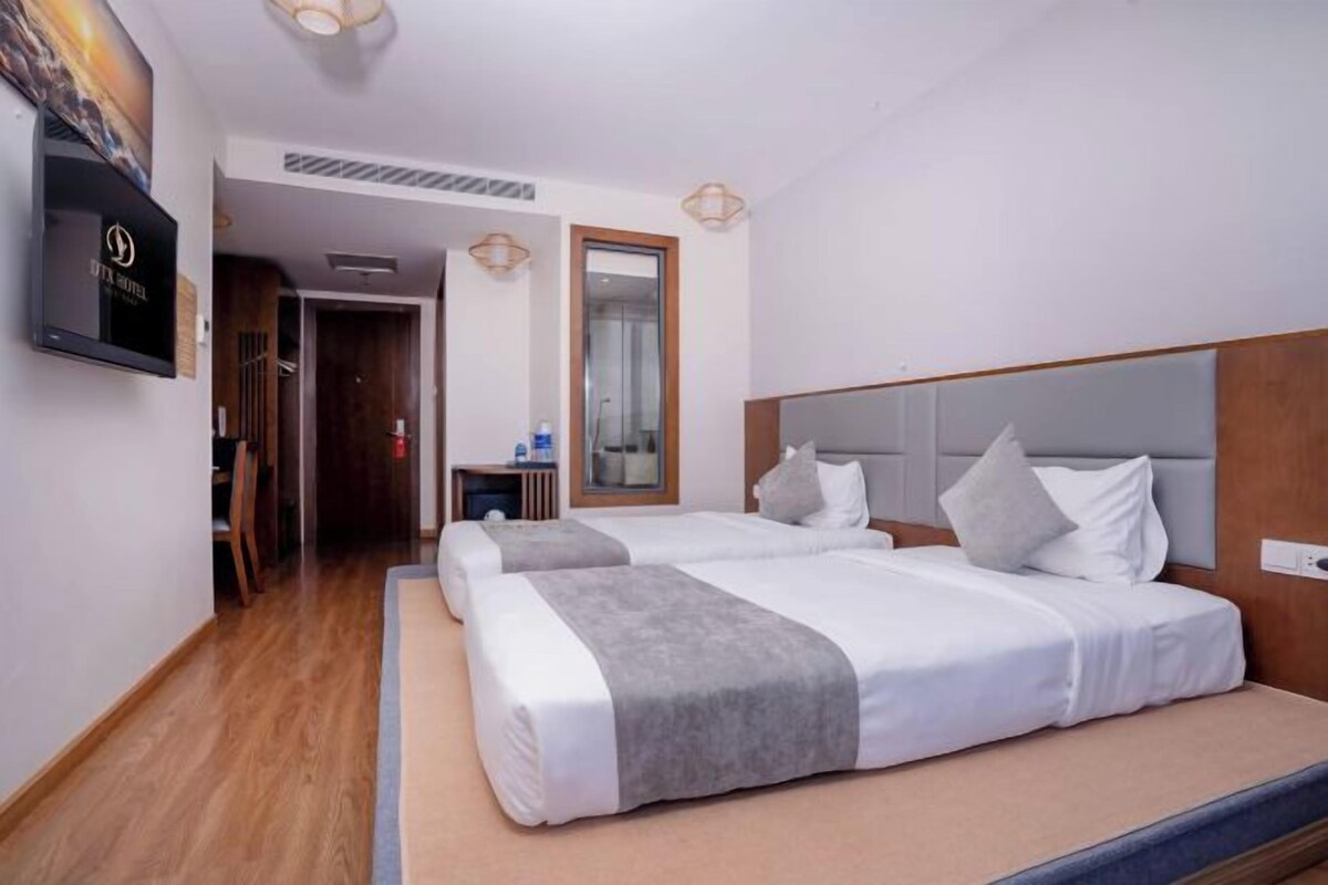 A hotel room with two beds, a television, and a mirror.