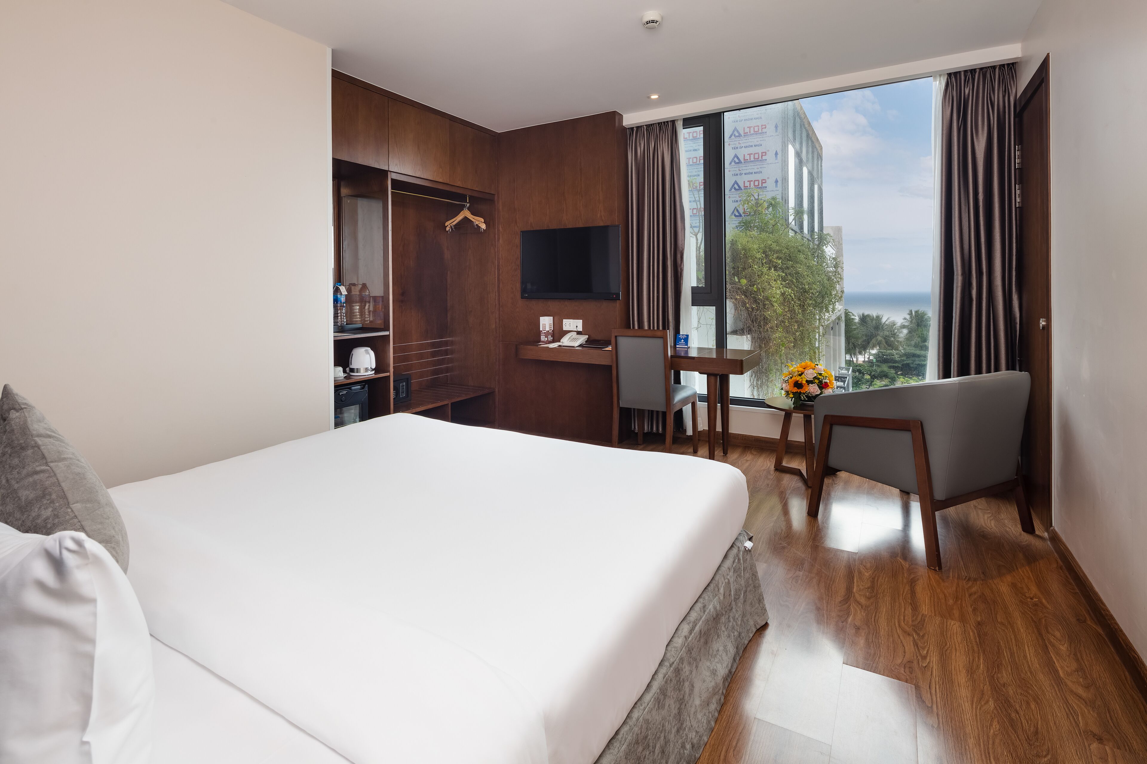 Habitación de hotel con una cama grande, un escritorio con silla, televisión y vistas a la ciudad.