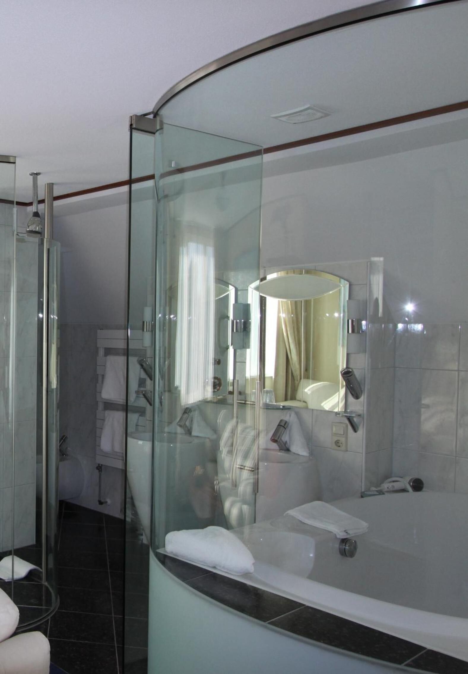 Un baño moderno con ducha de vidrio, un espejo grande y una bañera.