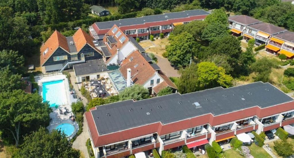 Un complex residencial amb diversos edificis, una piscina i una estructura de teulat pla.