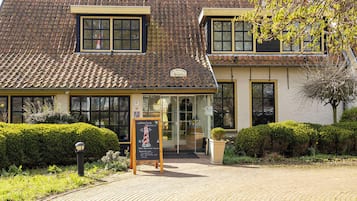 Un bâtiment avec un toit recouvert de tuiles et une enseigne devant l’entrée.
