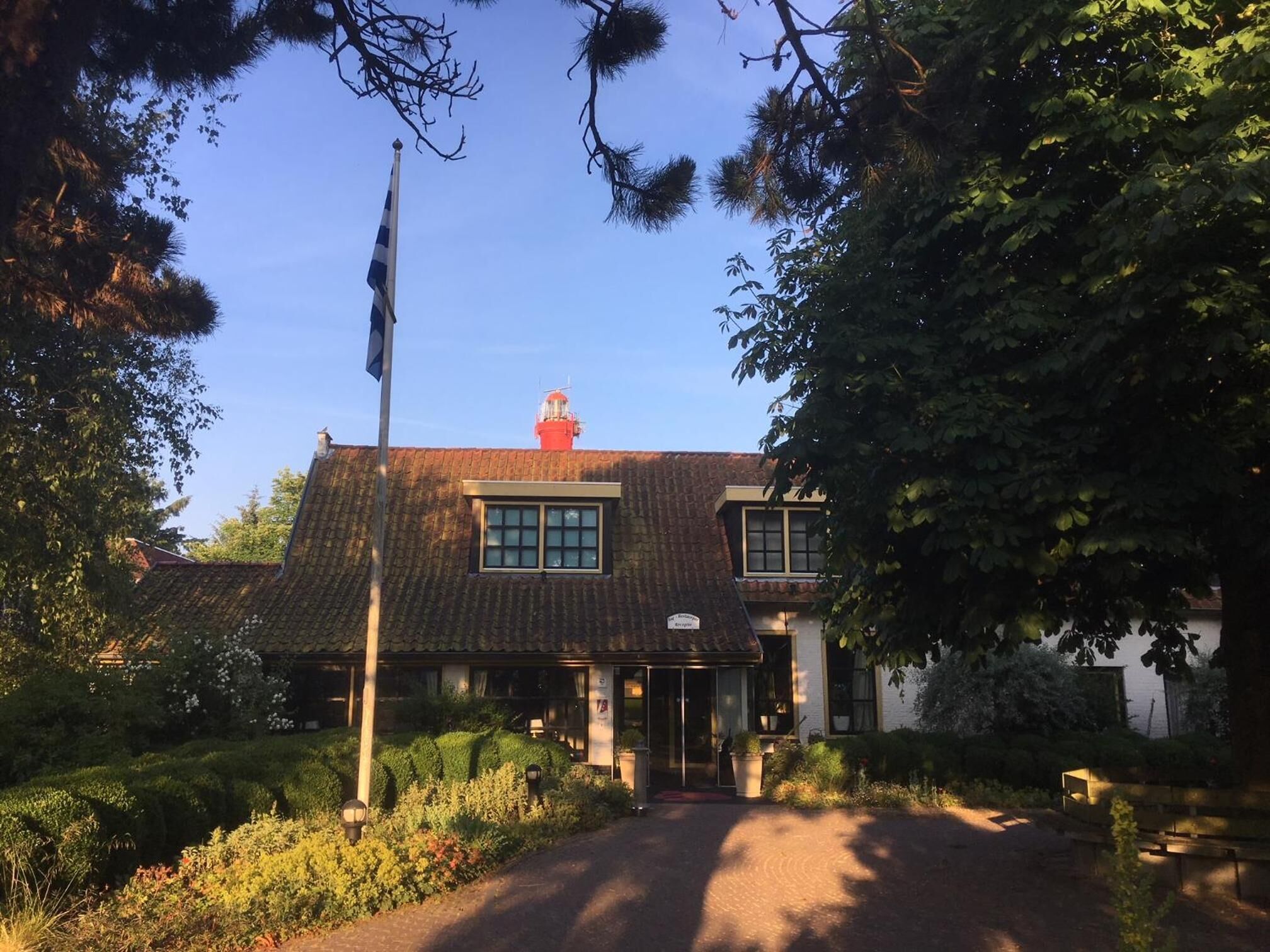 A traditional building with a tiled roof, a flagpole, and a small red tower.