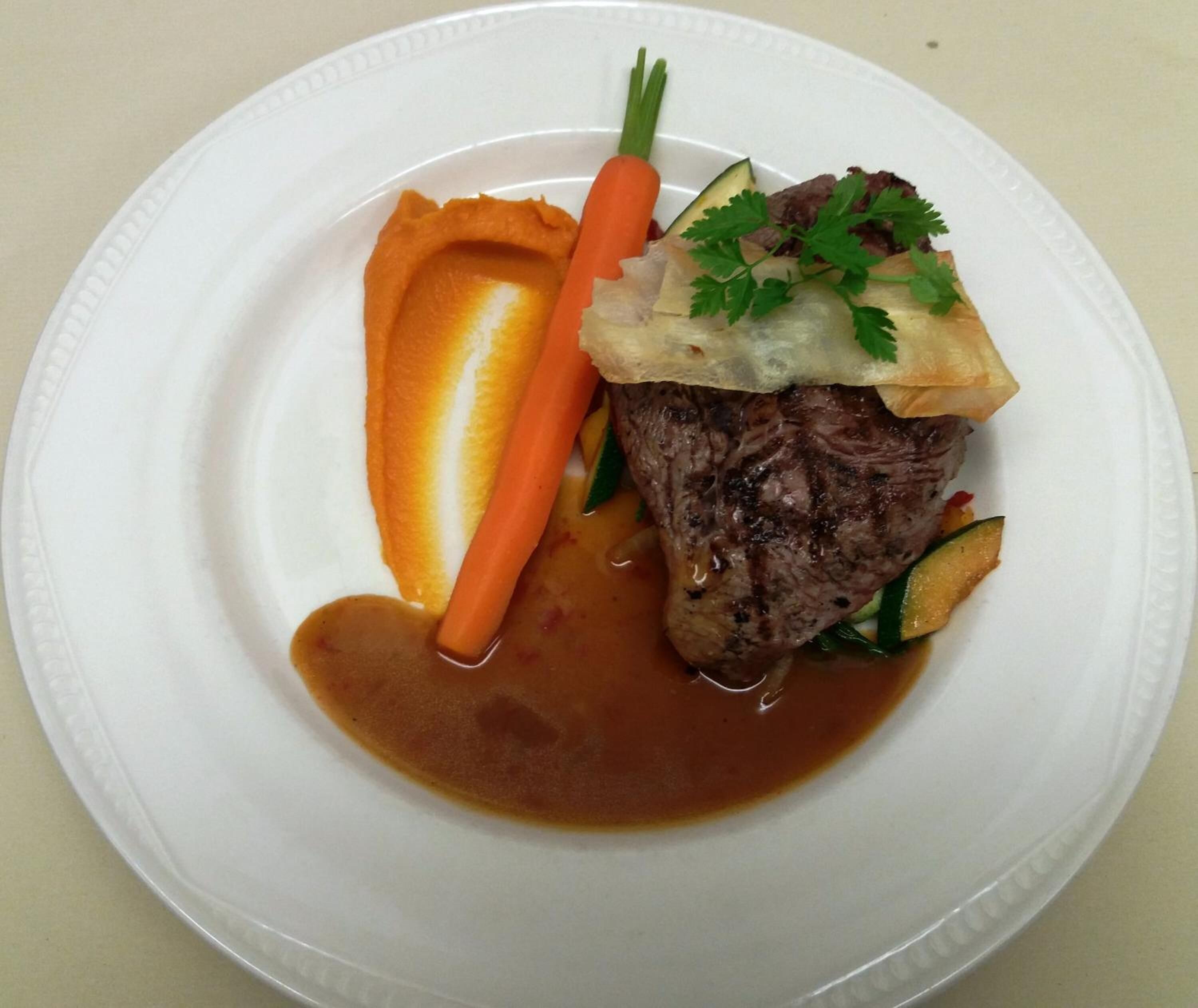 Un plato con un bistec, una zanahoria y una rebanada de pan.