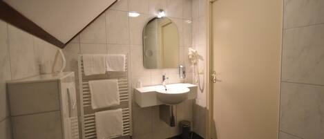 A bathroom with a toilet, sink, mirror, towel rack, and a door.
