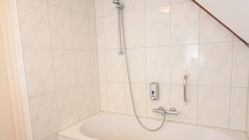 Een badkamer met een bad, douche en toilet.