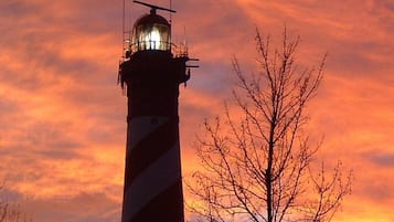 A lighthouse with a striped pattern, set against a sunset sky.