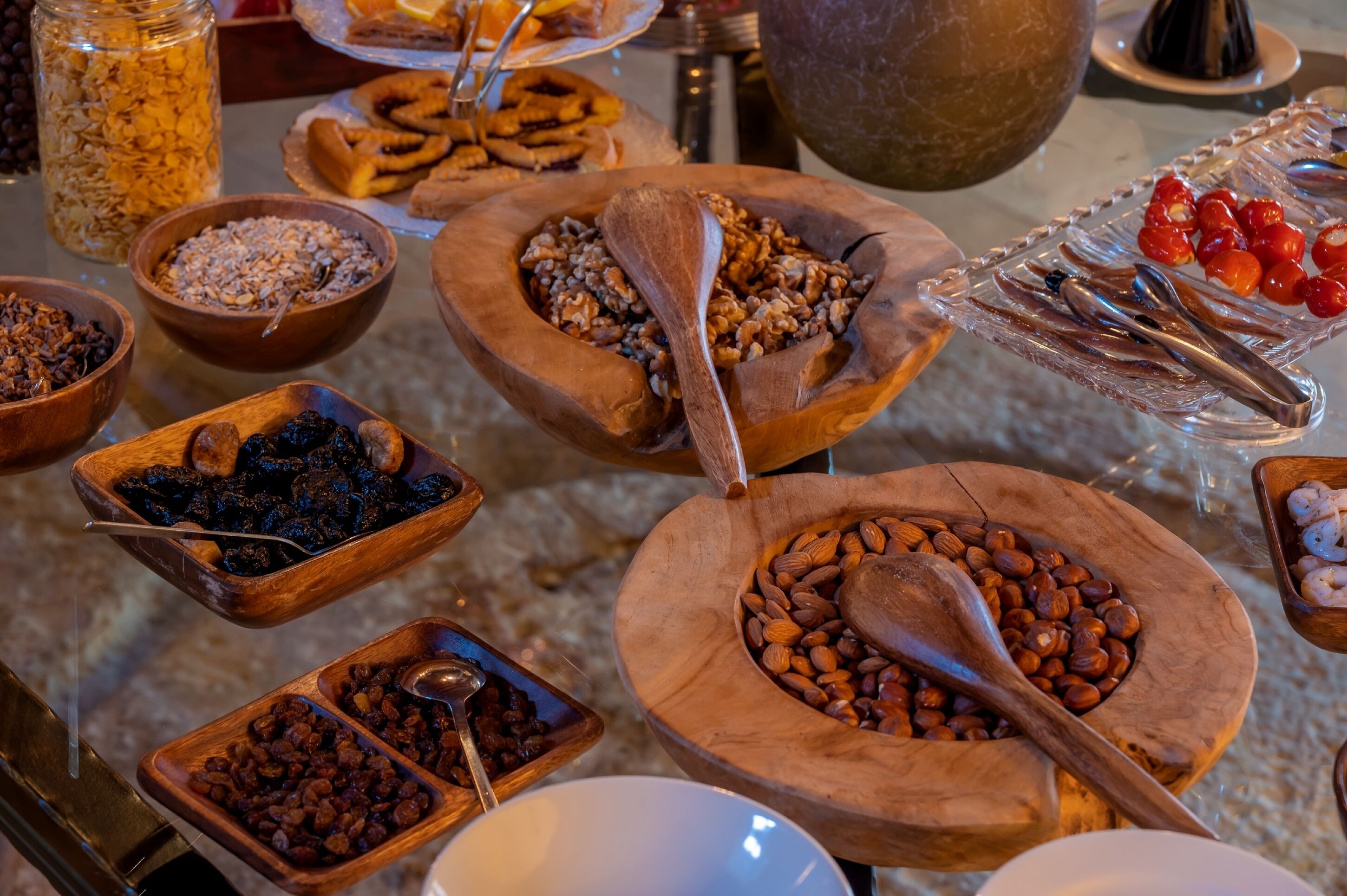Une table de buffet avec divers plats présentés dans des bols en bois et un plat en verre.