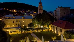 A historic building with a tower, surrounded by other structures and a well-maintained garden. - Puteus Palace Brac (Pucisca)