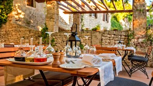 An outdoor dining area with wooden tables, white tablecloths, and various glassware and condiments. - Puteus Palace Brac (Pucisca)