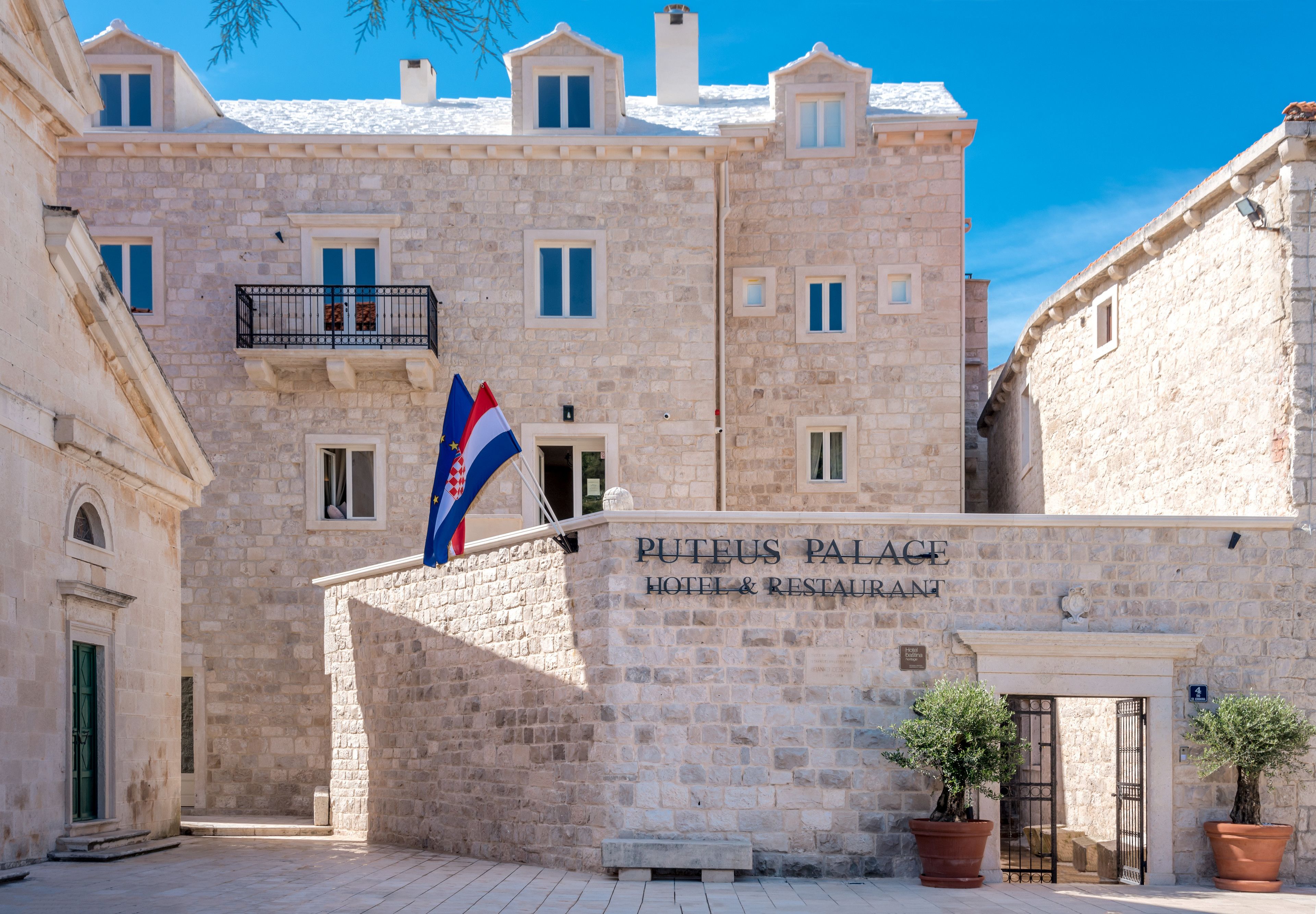 A stone building with a sign reading "Puteus Palace Hotel & Restaurant."