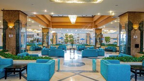 A spacious lobby with blue seating, a central fountain, and a chandelier. - Marlin Inn Azur Resort (Hurghada)