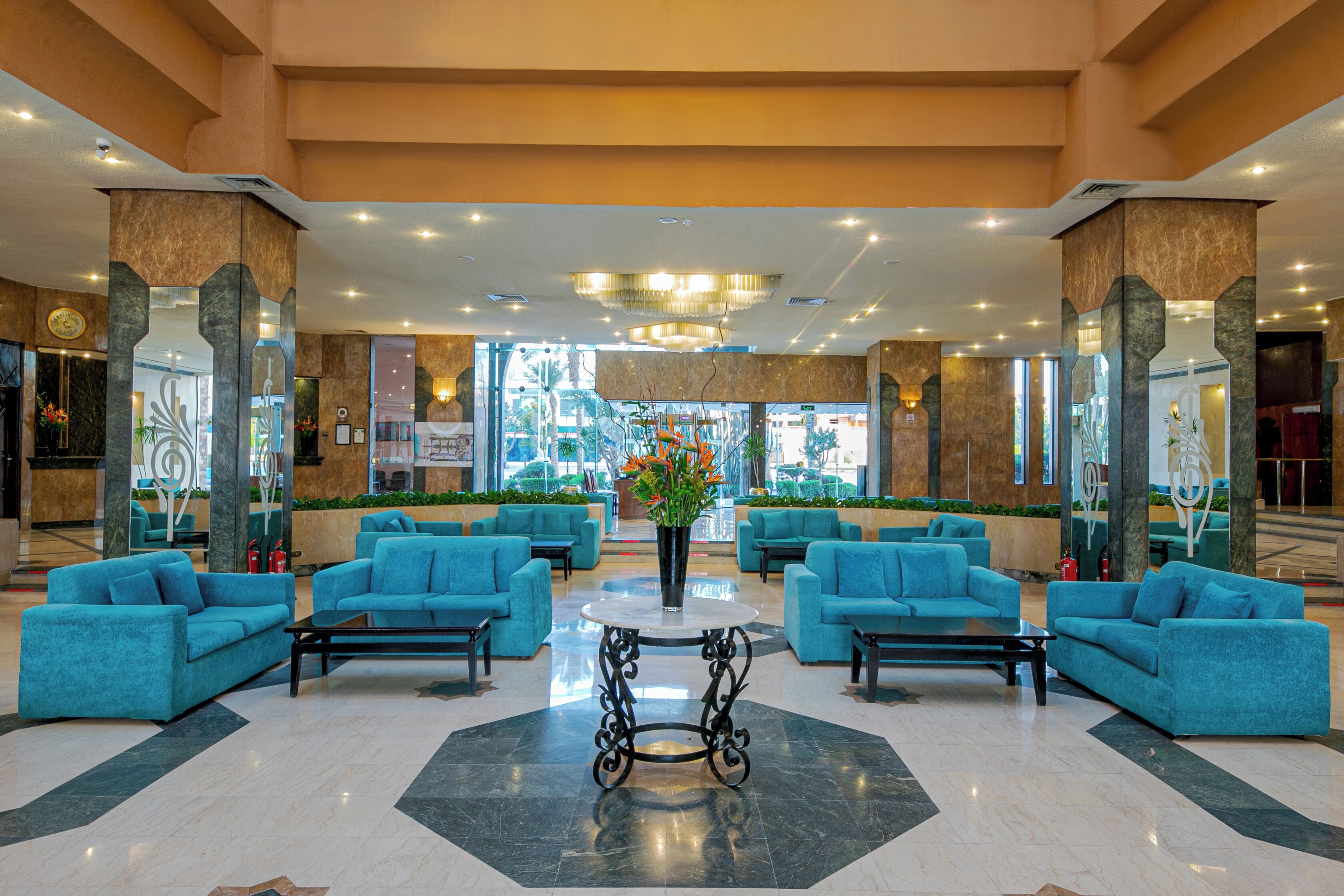 A lobby with teal sofas, a central table, and a chandelier.